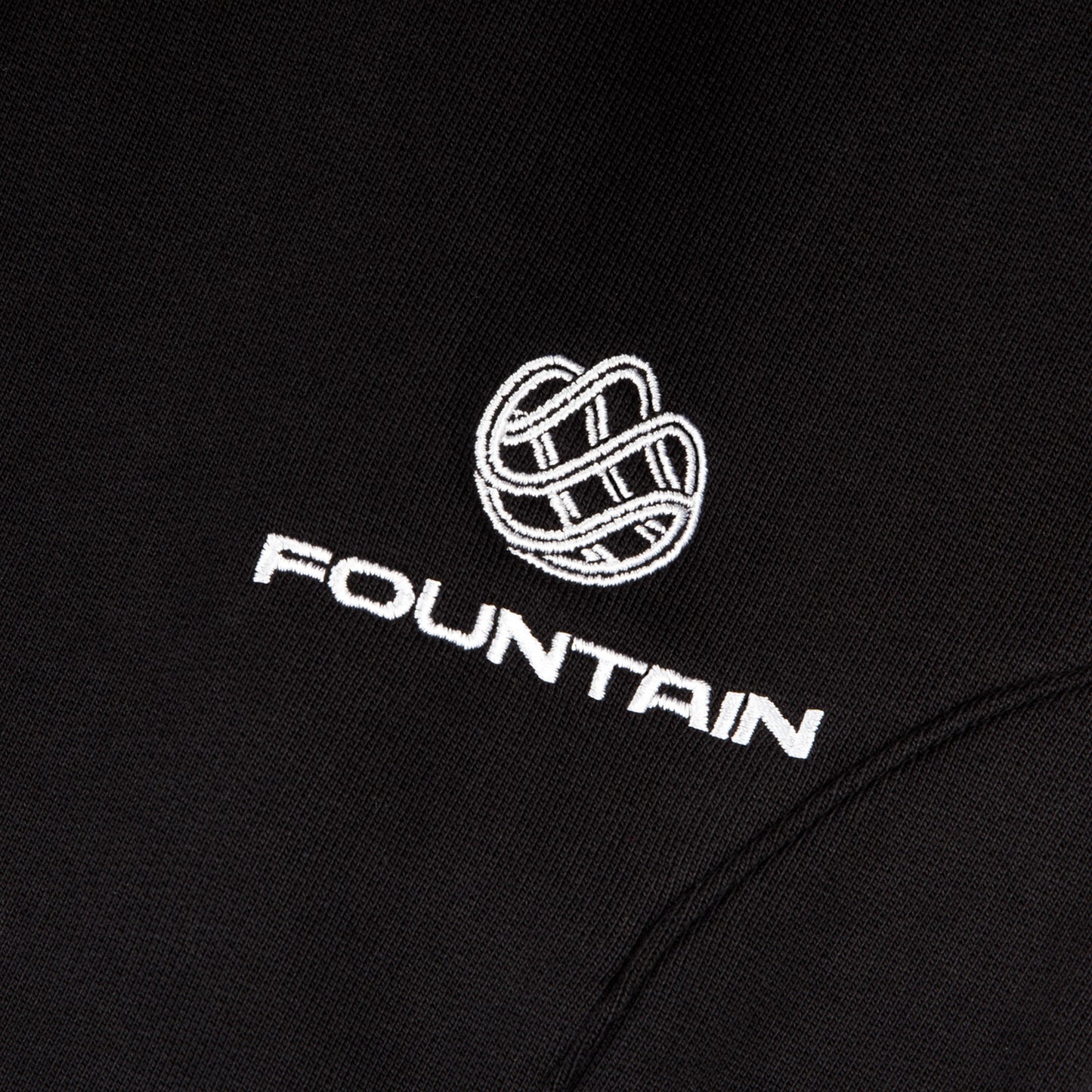 Close detail of the embroidered Fountain monogram at the left pocket